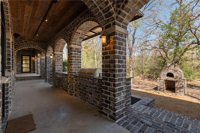 view of patio with area for grilling, a grill, and an outdoor brick fireplace