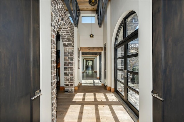 interior space featuring french doors, baseboards, wood finished floors, and a towering ceiling