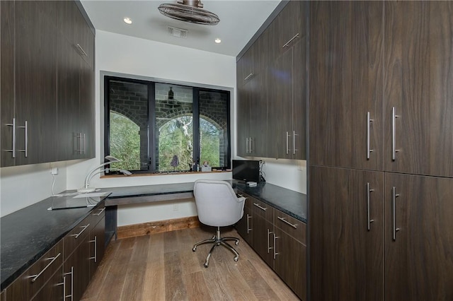 office space featuring visible vents, baseboards, dark wood finished floors, recessed lighting, and built in desk