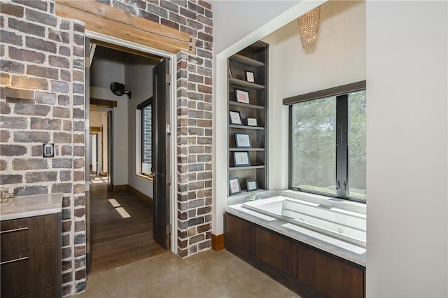 hall with baseboards, built in shelves, and concrete flooring