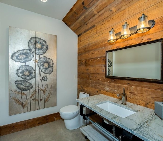 half bath with wood walls, toilet, vanity, and lofted ceiling