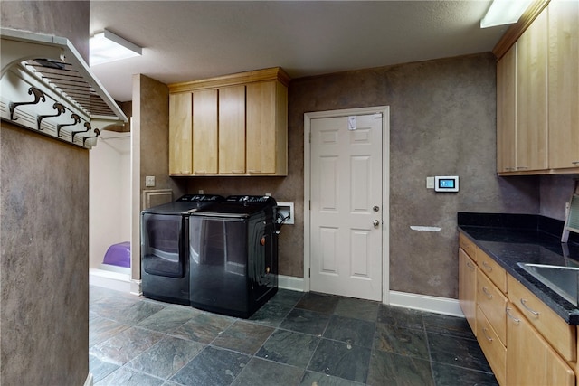 laundry room featuring cabinet space, baseboards, stone finish flooring, and washer and clothes dryer