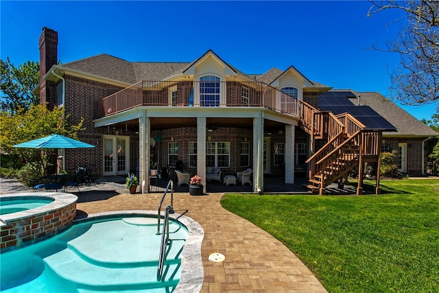 back of property with a balcony, a chimney, brick siding, a patio area, and a yard