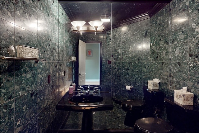 bathroom featuring a sink, ornamental molding, toilet, and tile walls