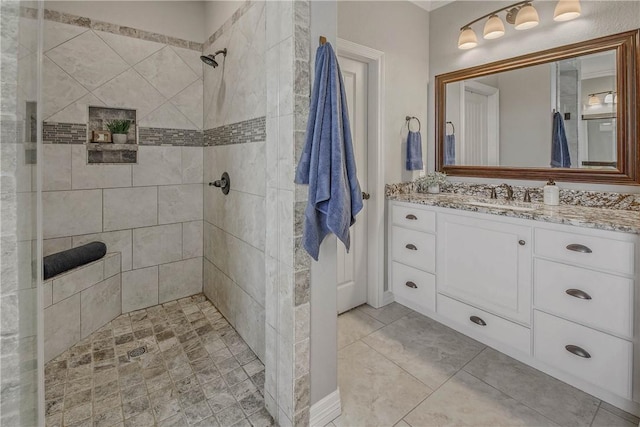 bathroom with tiled shower, vanity, and tile patterned floors