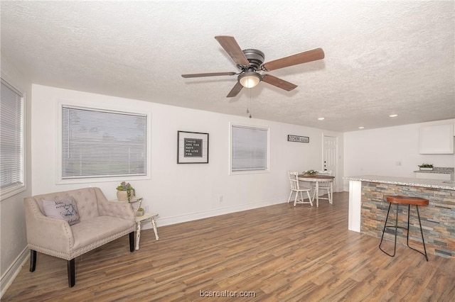 sitting room featuring a textured ceiling, ceiling fan, and dark hardwood / wood-style floors