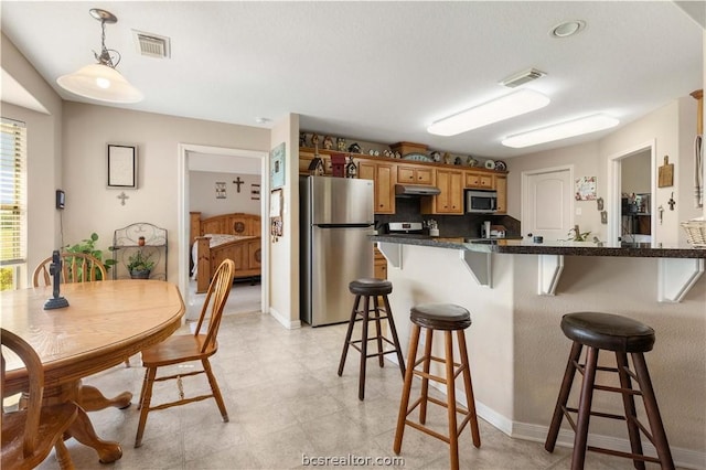 kitchen featuring a kitchen breakfast bar, decorative light fixtures, and appliances with stainless steel finishes