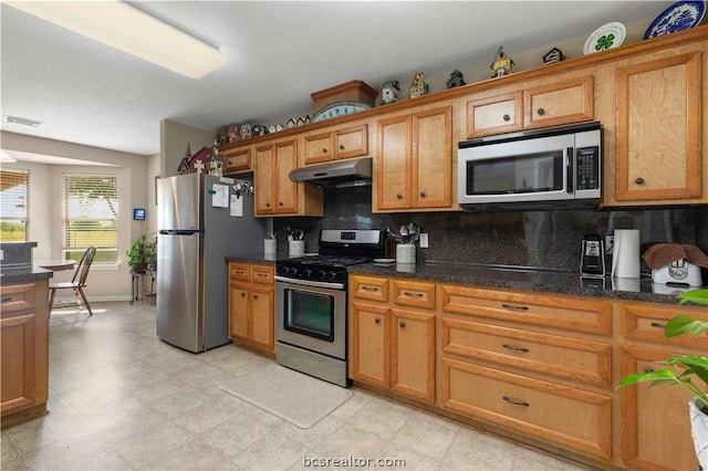 kitchen featuring backsplash, dark stone counters, and appliances with stainless steel finishes