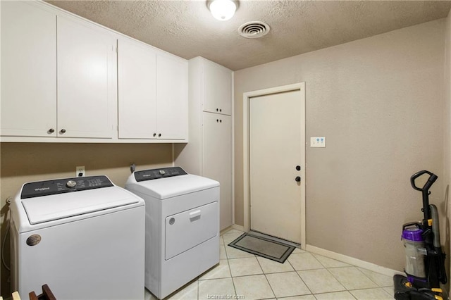 laundry area featuring separate washer and dryer, light tile patterned floors, cabinets, and a textured ceiling