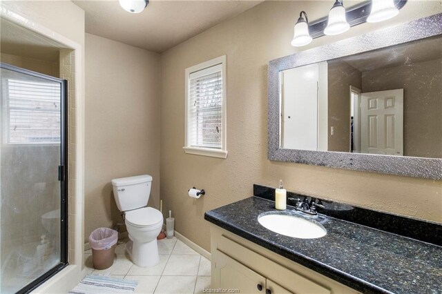 bathroom featuring tile patterned flooring, vanity, toilet, and a shower with shower door