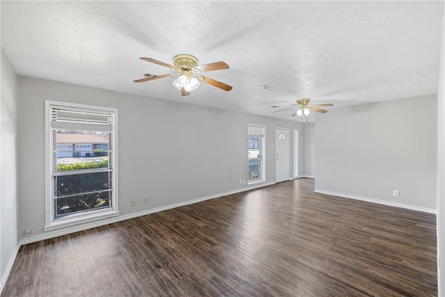 spare room featuring dark wood-type flooring, a textured ceiling, and a healthy amount of sunlight