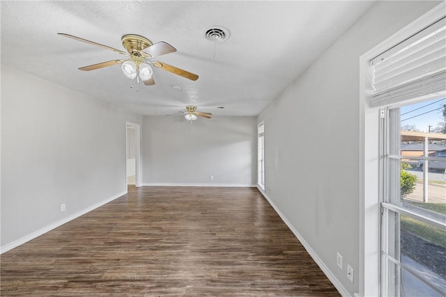 empty room with dark wood-type flooring, a wealth of natural light, and a textured ceiling