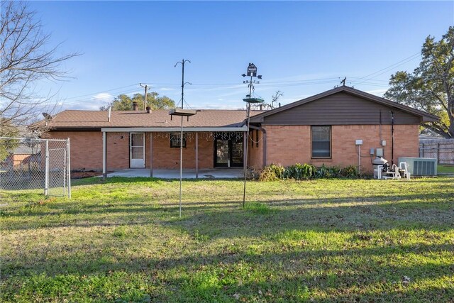 rear view of property featuring central AC unit, a yard, and a patio