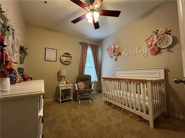bedroom with a nursery area, baseboards, ceiling fan, and dark colored carpet