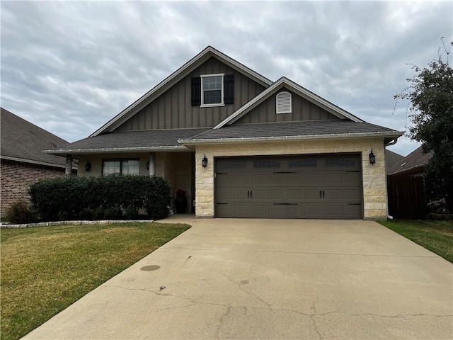 view of front of house with driveway, stone siding, an attached garage, board and batten siding, and a front yard