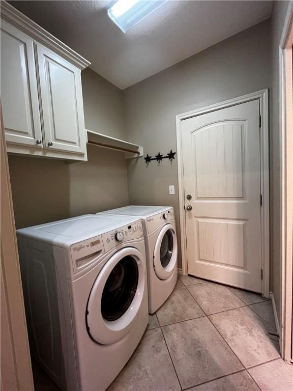 washroom with cabinet space, washing machine and dryer, and light tile patterned floors