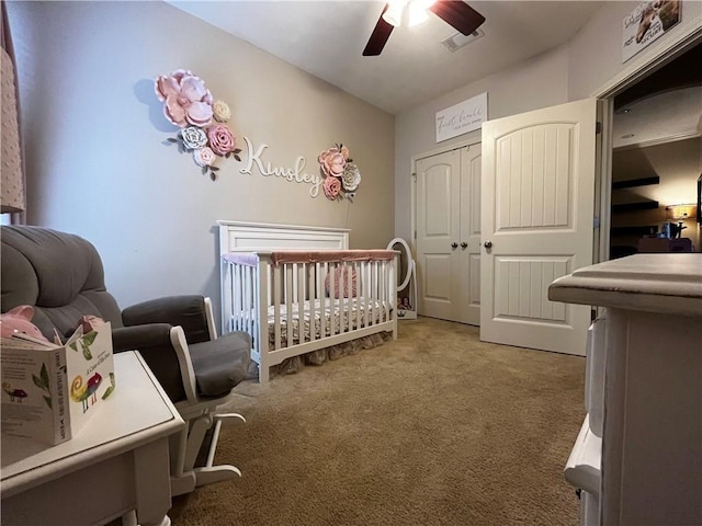carpeted bedroom featuring a crib, a closet, and a ceiling fan