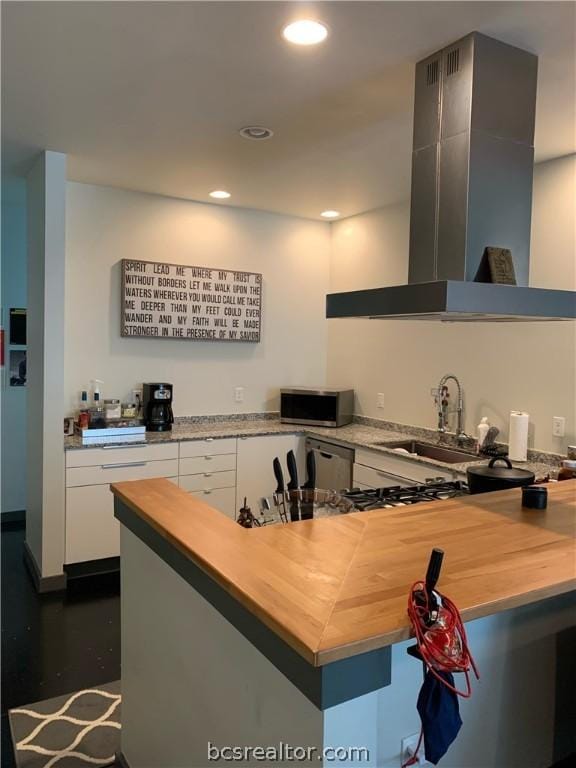 kitchen with wooden counters, sink, white cabinetry, and exhaust hood