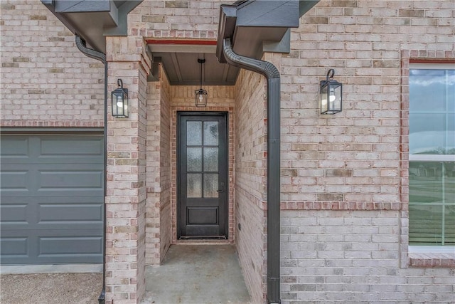 entrance to property featuring a garage and brick siding