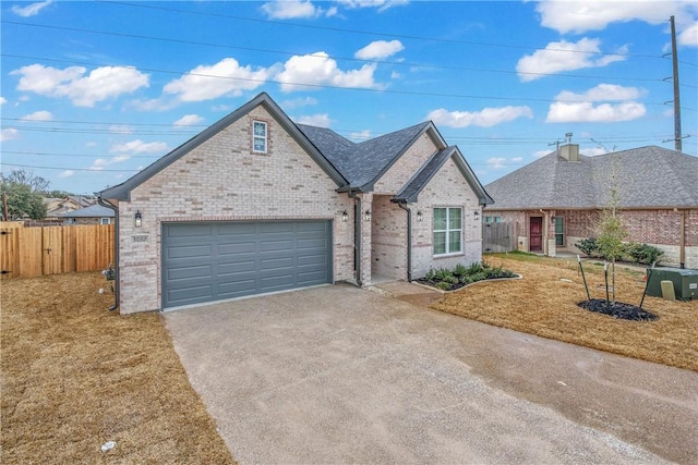 view of front of property featuring brick siding, fence, a garage, driveway, and a front lawn