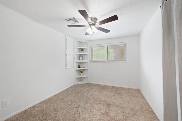 spare room with carpet flooring, a textured ceiling, baseboards, and visible vents