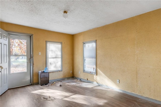 spare room with a textured ceiling and light hardwood / wood-style flooring