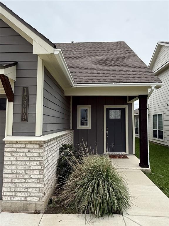 doorway to property featuring roof with shingles and covered porch