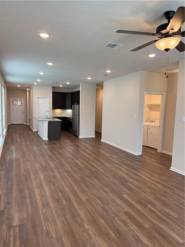 unfurnished living room with baseboards, a ceiling fan, dark wood-style flooring, and independent washer and dryer