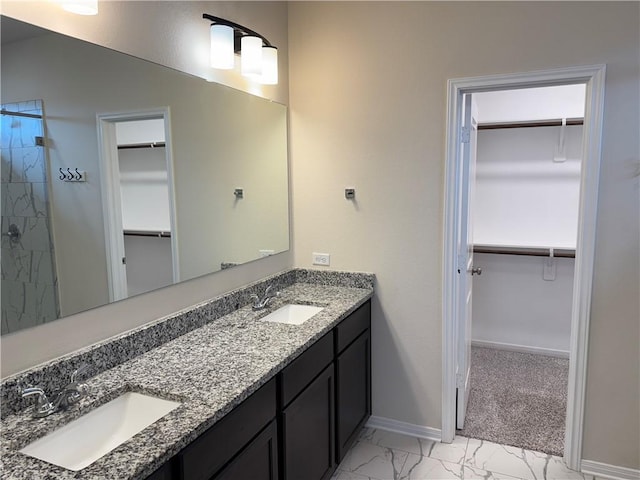 bathroom featuring double vanity, tiled shower, a sink, and marble finish floor