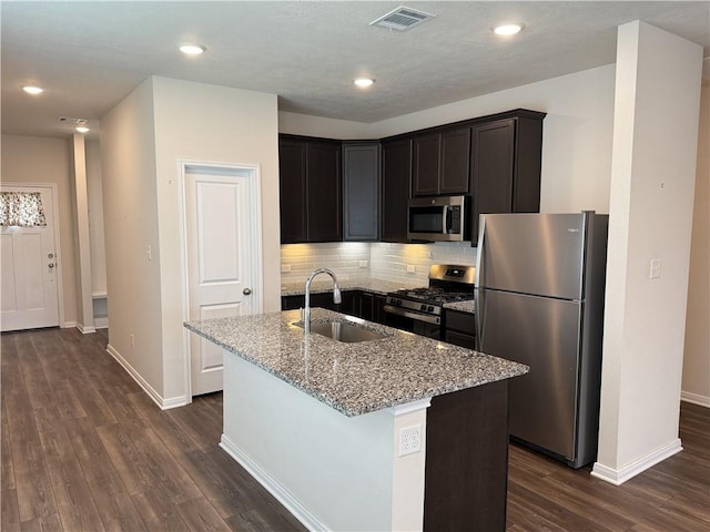 kitchen with visible vents, appliances with stainless steel finishes, a sink, light stone counters, and dark wood-type flooring