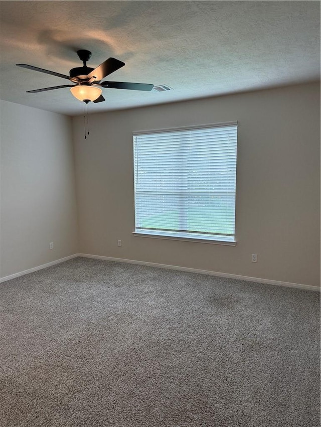 carpeted empty room featuring a textured ceiling, ceiling fan, visible vents, and baseboards