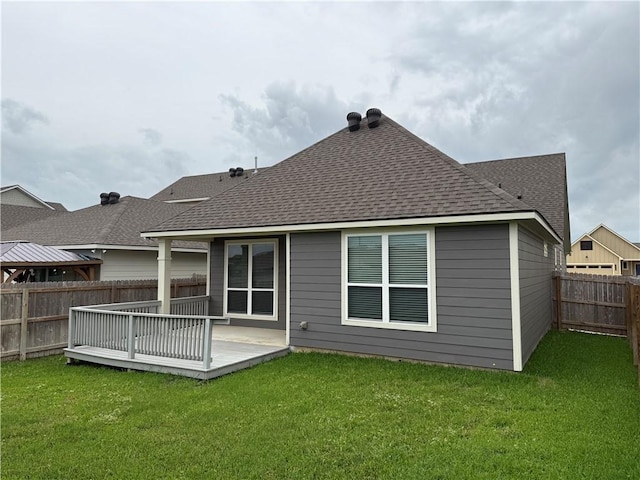 rear view of property featuring a fenced backyard, a shingled roof, and a lawn