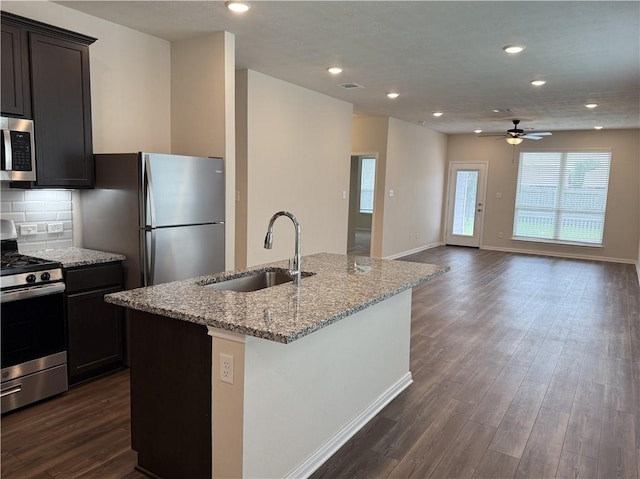 kitchen with a ceiling fan, a sink, appliances with stainless steel finishes, and dark wood-type flooring