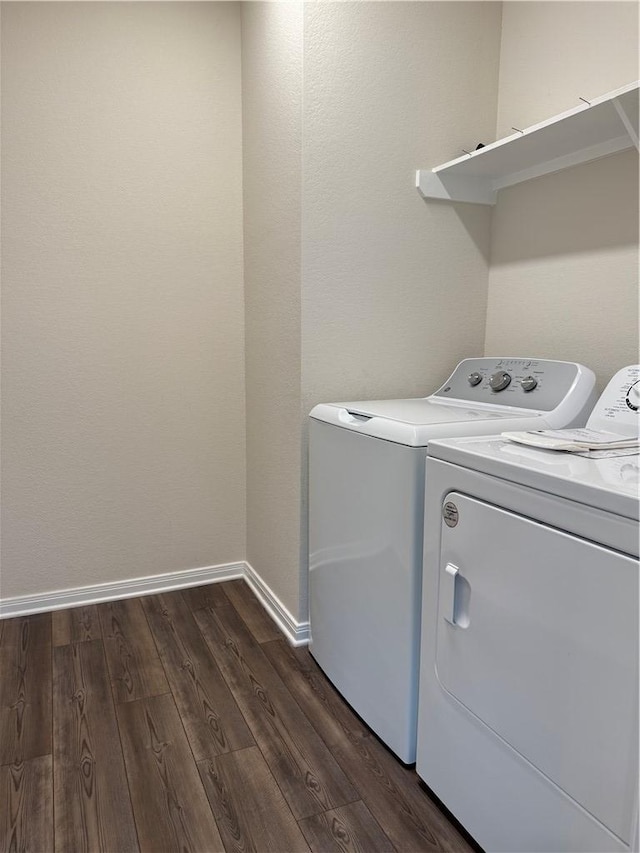 clothes washing area featuring laundry area, washer and clothes dryer, baseboards, and dark wood-style floors