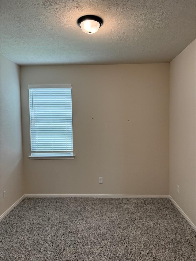 carpeted spare room with baseboards and a textured ceiling