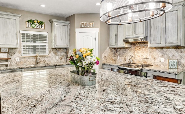 2102 Cary Cir, Bryan, TX 77803 - kitchen featuring under cabinet range hood, a chandelier, light stone counters, decorative backsplash, and recessed lighting