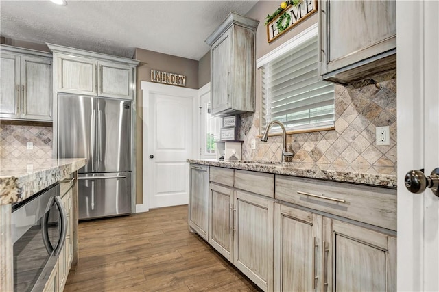2102 Cary Cir, Bryan, TX 77803 - kitchen featuring stainless steel refrigerator, wood finished floors, decorative backsplash, and light stone countertops