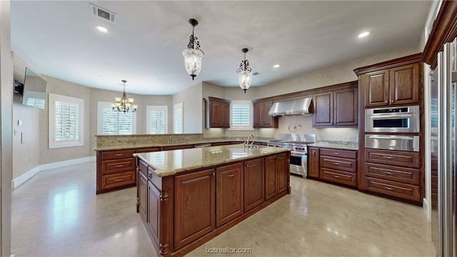 kitchen featuring a center island with sink, wall chimney exhaust hood, appliances with stainless steel finishes, decorative light fixtures, and a chandelier