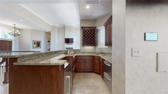 kitchen featuring sink, hanging light fixtures, a notable chandelier, kitchen peninsula, and a kitchen bar