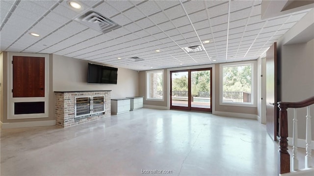 unfurnished living room with a drop ceiling and a brick fireplace