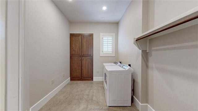 laundry area with washing machine and clothes dryer and cabinets