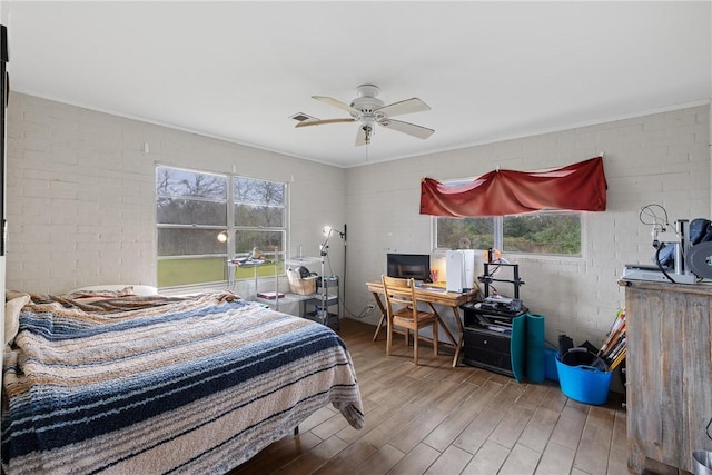 bedroom with hardwood / wood-style floors, ceiling fan, crown molding, and brick wall