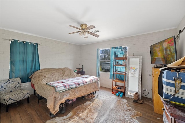 bedroom featuring ceiling fan, dark wood-type flooring, and brick wall