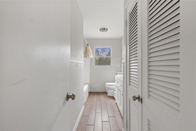 bathroom featuring crown molding, shower / washtub combination, tile walls, and toilet