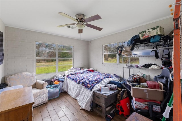 bedroom with ceiling fan and brick wall