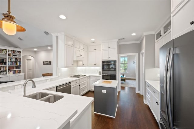 kitchen featuring sink, appliances with stainless steel finishes, light stone counters, white cabinets, and a kitchen island