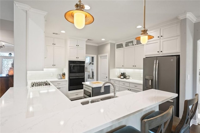 kitchen featuring light stone counters, kitchen peninsula, sink, and white cabinets