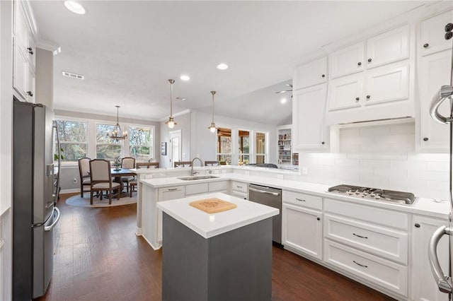 kitchen with appliances with stainless steel finishes, a kitchen island, hanging light fixtures, and kitchen peninsula