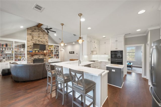 kitchen with white cabinetry, appliances with stainless steel finishes, a kitchen breakfast bar, kitchen peninsula, and pendant lighting