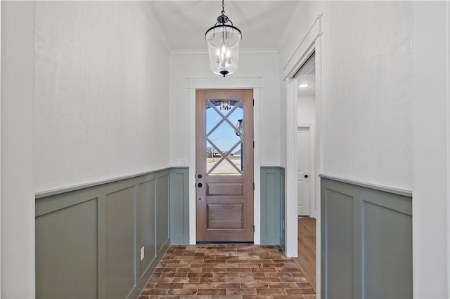 doorway with crown molding and an inviting chandelier